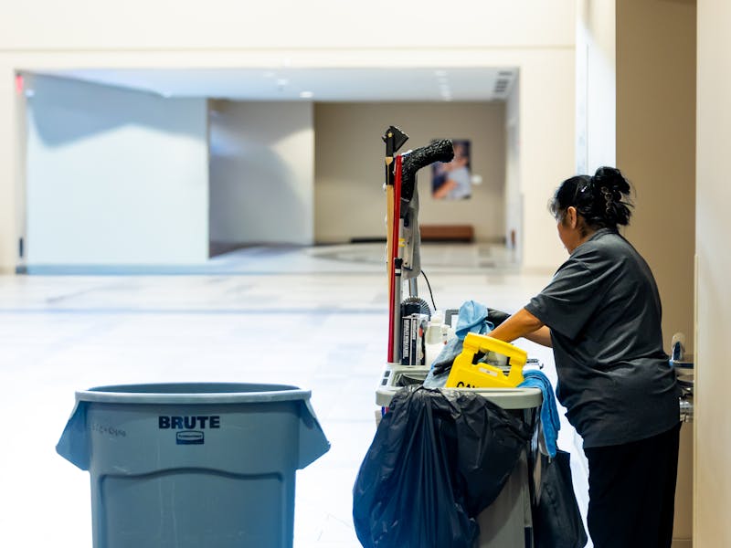 Janitor pushing a supply cart through a building hallway